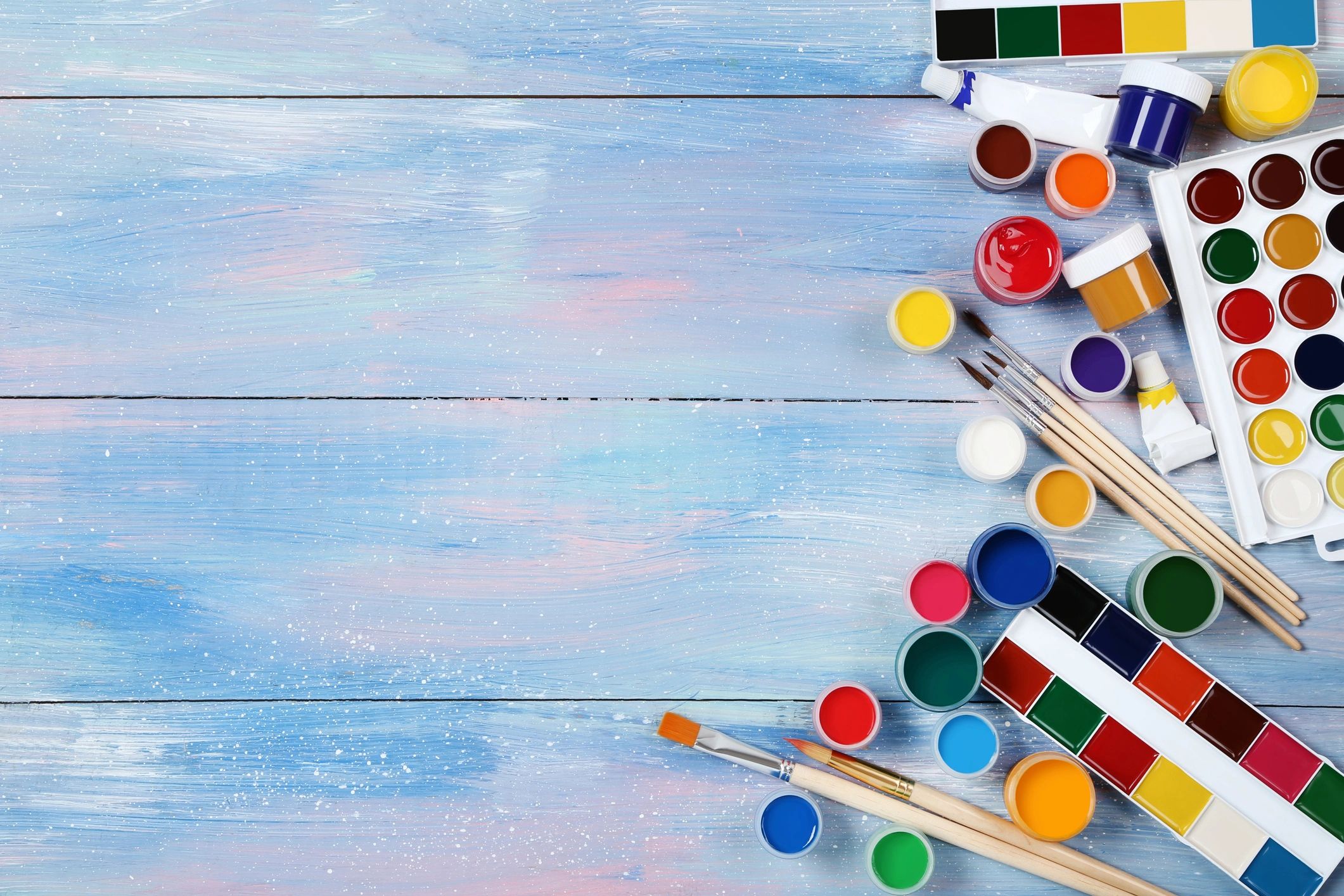 Paints and brushes arranged on a blue work surface